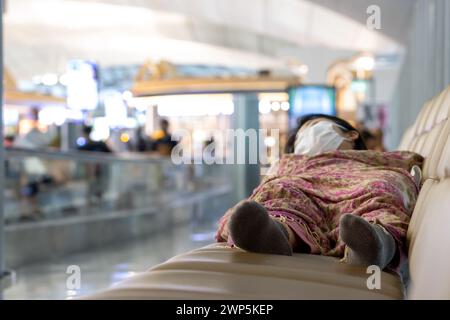 A sleeping person on the seats in the corridor of an international airport, focus on a feet Stock Photo