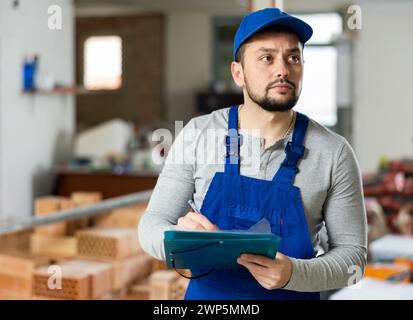 Foreman making task list during works in building under construction Stock Photo