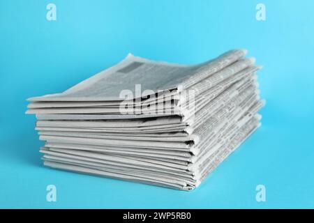 Stack of newspapers on light blue background. Journalist's work Stock Photo