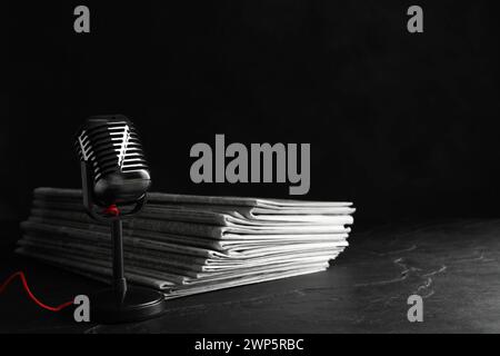 Newspapers and vintage microphone on dark stone table. Journalist's work Stock Photo
