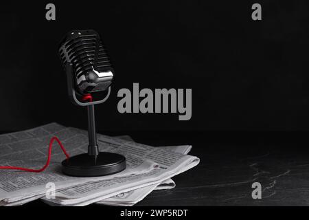 Newspapers and vintage microphone on dark stone table, space for text. Journalist's work Stock Photo