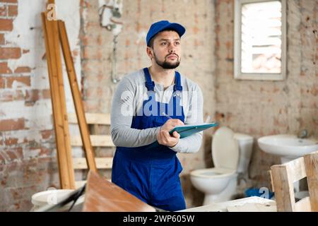 Builder making notes on indoor construction site Stock Photo