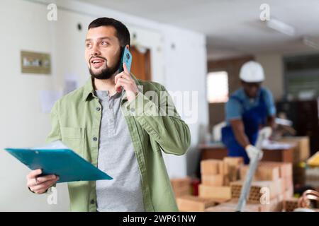 Construction manager with paper folder having telephone conversation Stock Photo
