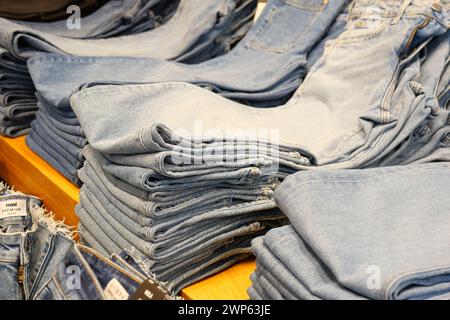 Piles of denim jeans stacked on a table  Stock Photo