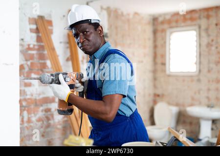 Portrait of builder using electric hammer in apartment Stock Photo