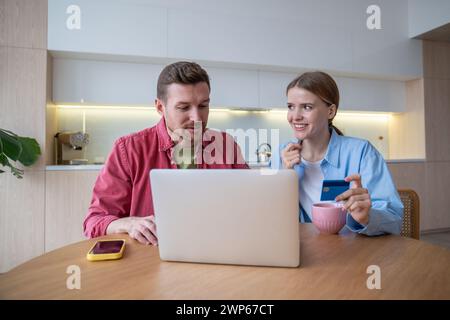 Millennial couple makes great deals online using laptop of comfort home. Convenience online shopping Stock Photo
