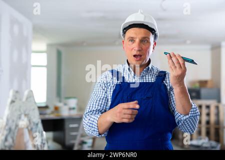 Foreman using smartphone, recording voice message Stock Photo