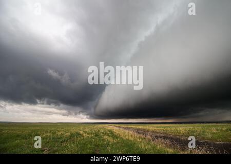 A massive shelf cloud approaches over a flat grassland, bringing rain, wind, and stormy weather. Stock Photo