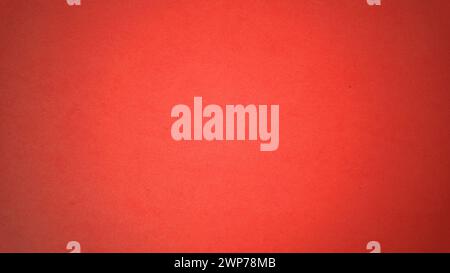 A sheet of bright red paper with light vignetting around the edges. Passionate red color. Saturated bright paint. Paper texture. Background for greeti Stock Photo