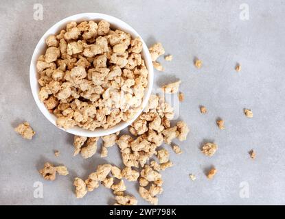 uncooked soya chunks in bowl on a mottled grey surface with copy space Stock Photo
