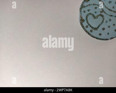 Gray background. At the top right, a decorative detail of blue paper made of silver with sequins arranged in the form of a heart and smooth rounded Stock Photo