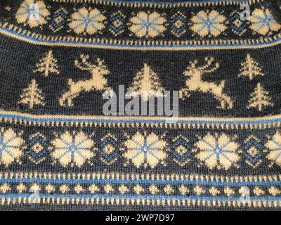 A fragment of an ornament on a knitted polyester or woolen sweater. Winter motives. Blue threads for hand knitting. White thread knitted pattern. Flow Stock Photo