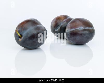 Three plums isolated on white background close up with reflection Stock Photo