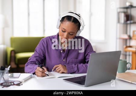 Dedicated black female student taking notes from an online class Stock Photo