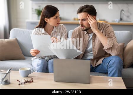 Worried couple reviewing finances with laptop and papers Stock Photo