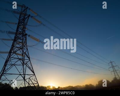 I love electricity pylons; I find their abstract, gaunt shapes endlessly fascinating. Here we see two giant pylons in a field by the Thames at Kenning Stock Photo