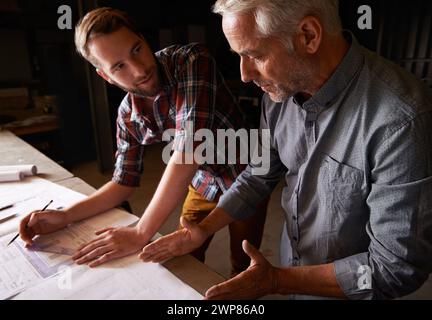 Carpenter, team and men with blueprint for discussion of construction project or father teaching son. Engineer, apprentice and senior mentor with Stock Photo