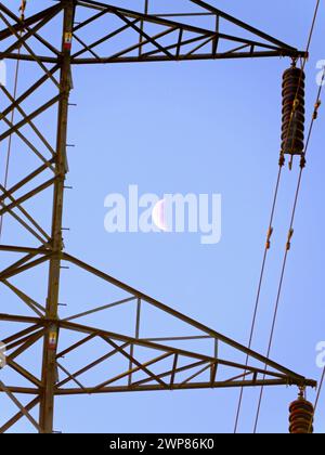 I love electricity pylons; I find their abstract, gaunt shapes endlessly fascinating. And here is a new viewpoint - a crescent half- moon seen though Stock Photo