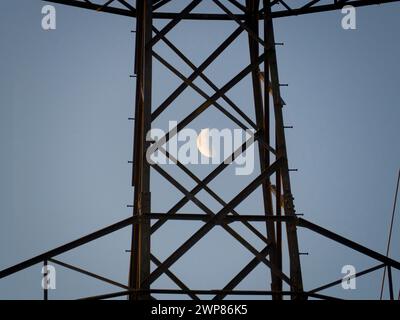 I love electricity pylons; I find their abstract, gaunt shapes endlessly fascinating. And here is a new viewpoint - a crescent half- moon seen though Stock Photo