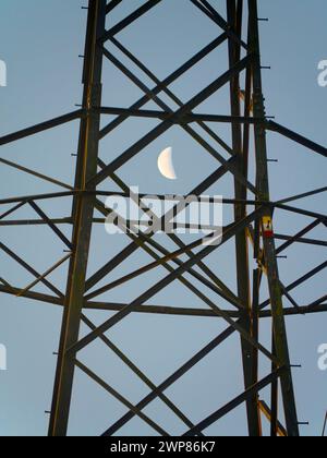 I love electricity pylons; I find their abstract, gaunt shapes endlessly fascinating. And here is a new viewpoint - a crescent half- moon seen though Stock Photo