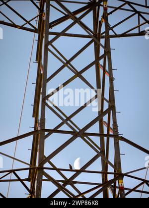 I love electricity pylons; I find their abstract, gaunt shapes endlessly fascinating. And here is a new viewpoint - a crescent half- moon seen though Stock Photo