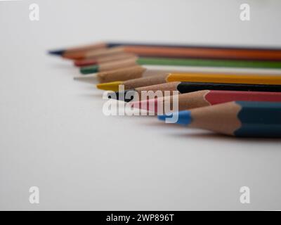 A close-up of assorted colorful pencils arranged on a white table surface Stock Photo