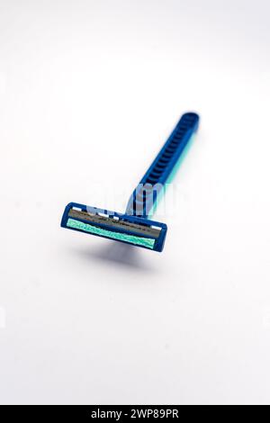 Closeup of used blue disposable razor that is dirty and rusty isolated on white background. Made of plastic and used to shave mustaches and beards. Stock Photo