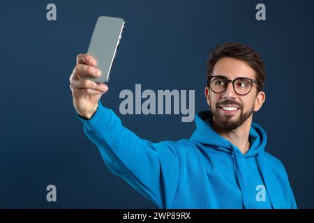 Handsome young man in eyeglasses taking selfie on smartphone Stock Photo