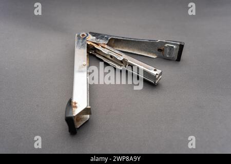 A used rusty stapler.A tool for holding together a number of pieces of paper which are usually made of metal.Isolated on dark background. Stock Photo