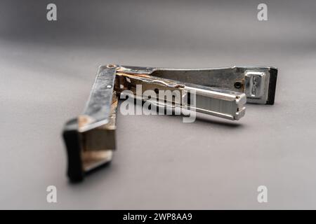 A used rusty stapler.A tool for holding together a number of pieces of paper which are usually made of metal.Isolated on dark background. Stock Photo