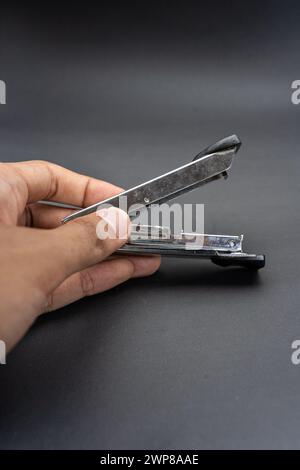 A used rusty stapler.A tool for holding together a number of pieces of paper which are usually made of metal.Isolated on dark background. Stock Photo