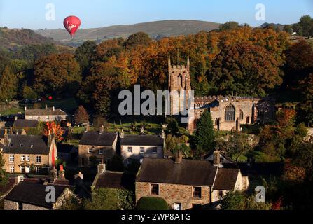 09/10/12.  A hot air balloon glides over The Peak District as the early morning sun bathes Hartington, Derbyshire in a riot of Autumn colour.   All Ri Stock Photo