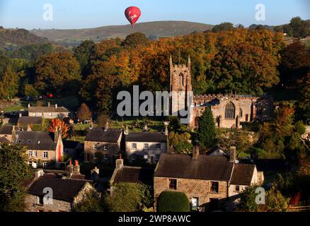 09/10/12.  A hot air balloon glides over The Peak District as the early morning sun bathes Hartington, Derbyshire in a riot of Autumn colour.   All Ri Stock Photo