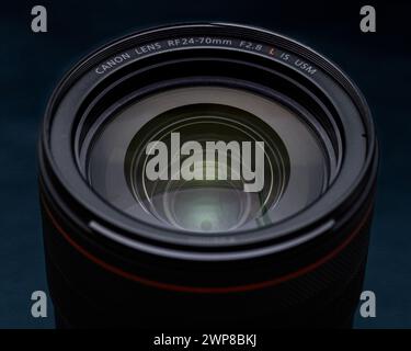 A Canon RF 24-70 F2.8 IS USM mirrorless full frame lens on a dark background Stock Photo