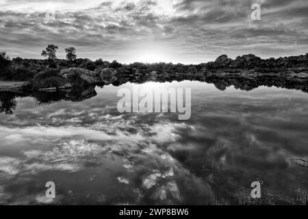 A grayscale shot of a sunny sky over a lake in Barruecos, Extremadura, Spain Stock Photo