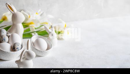White Easter banner. Traditional Easter decorations eggs, ceramic bunnies, white Iris flowers on white background. Elegant invitation template. Copy s Stock Photo