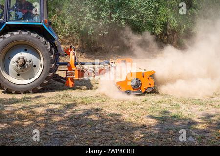 tractor with a mulcher crushes and levels the top layer of soil. Agricultural work. Stock Photo