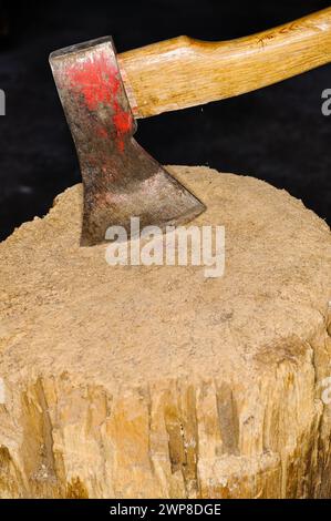 An Ax with wood handle is stuck in a wood Stock Photo