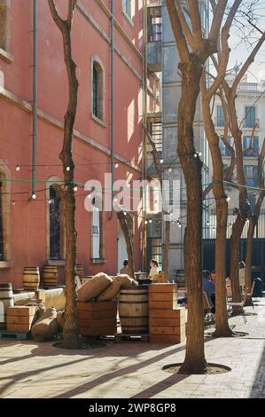 Barcelona, Spain - March 06, 2024: Vintage urban scene with wooden barrels, sacks and trees, creating a relaxed and nostalgic atmosphere. Stock Photo