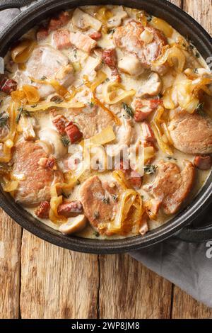 Seared pork tenderloin braised with mushrooms and bacon in a creamy sauce and served with caramelized onions close-up in a frying pan on the table. Ve Stock Photo