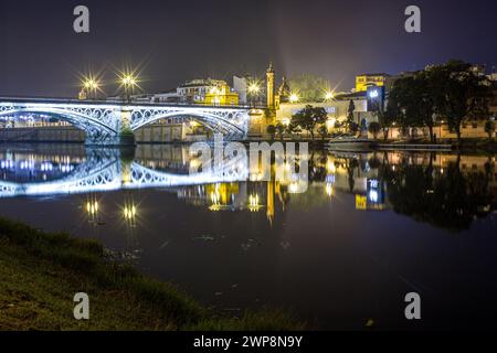 The Triana Bridge and Capillita del Carmen illuminated at night with long exposure. Stock Photo