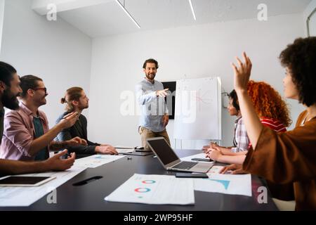 Smiling diverse colleagues gather in boardroom brainstorm discuss financial statistics together Stock Photo