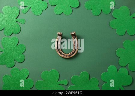 St. Patrick's day border with clover leaves and horseshoe on green background. View from above. Copy space. Festive greeting card. Stock Photo
