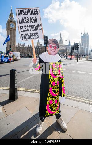 London UK 9 Mar 2024 A Man Holds A Banner Arrest The War Criminals   London Uk 6th Mar 2024 Arseholes Liars And Elecronic Pioneers A One Man Protest By The Band Paranoid London In And Elton John Mask Protesters Gather Outside As Jeremy Hunt Mp Chanceellor Of The Exchequer Delivers The Budget In Parliament On Budget Day In Westminster London Credit Guy Bellalamy Live News 2wp9666 