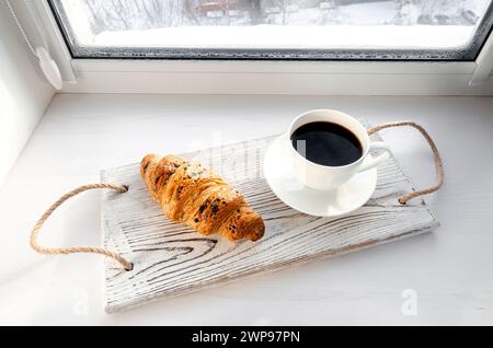 Traditional breakfast. Coffee and croissant on a tray on the windowsill Stock Photo