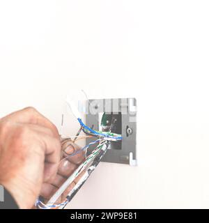 Electrician's hands when installing the socket and connecting the Internet Stock Photo