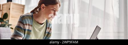 horizontal banner of focused teenager doing homework at home, gen z girl looking at laptop Stock Photo
