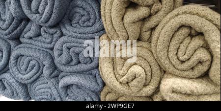 Soft fluffy beige, gray and blue plaids, rolled up in skeins, rolls and bundles. An assortment of different bedspreads on a store shelf. The blankets Stock Photo