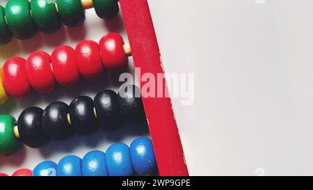 Wooden abacus. Red wooden frame with cross rods. Red, blue, yellow, green, black wooden elements. Math tool on a white background. Close-up. Copy Stock Photo
