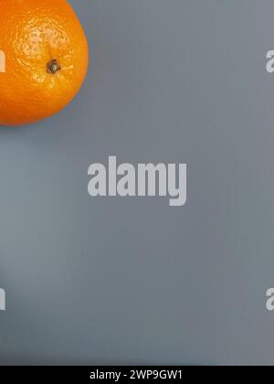 Beautiful bright orange orange with shiny thick peel on a gray background. Fruit bottom left. Free space for text. Healthy citrus fruits. Vitamins of Stock Photo